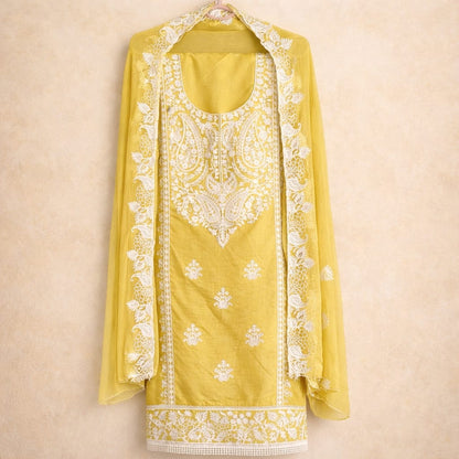 Mustard yellow Marjeena Lucknowi Chikankari unstitched suit set with paisley embroidery, fabric details visible in the image.